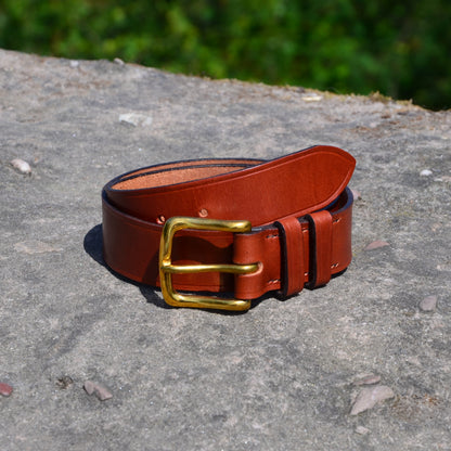 vegetable tanned tan leather belt brass buckle on a rock