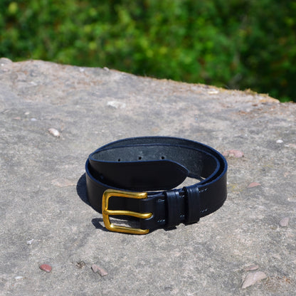 vegetable tanned black leather belt brass buckle on a rock