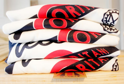 Pile of Men’s British-made white cotton Enjoy graphic T-shirts by Meccanica with vintage racing-style screen print.